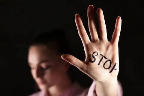 Woman with word Stop written on hand against dark background, closeup. Dome.. Stock Photos