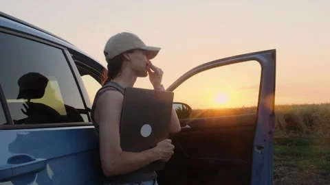A woman in work clothes stands next to the car in the fields at sunset. Vídeos de archivo 339676441