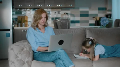 Woman work with computer laptop while her daughter in painting on couch Rbbro Stock Footage 135805748