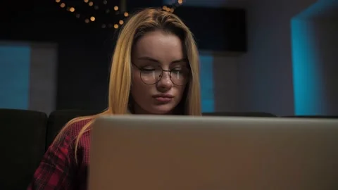 Woman work remotely using laptop sitting at couch in home interior.Serious Stock Footage 225654753