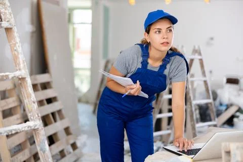 Woman worker checking documents and using laptop in construction site Stock Photos