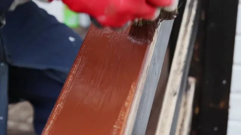 Woman worker in gloves paints the top surface of the wooden handrail brown Vídeo Stock 143195053