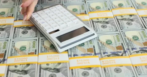 Woman worker places calculator on stack of dollar packs Stock Footage 279005582