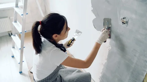 Woman worker using a spatula painting walls in the apartment or house. Stock Footage