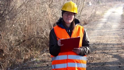 Woman worker writing notes down on her clipboard on the country road Stock Footage 73709216