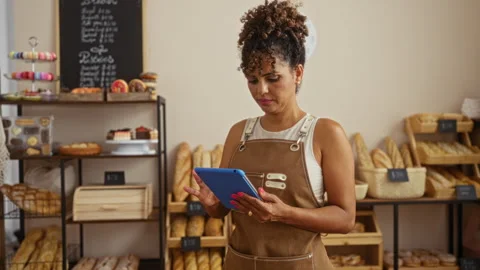 Woman working in a bakery using a tablet surrounded by various breads and p.. Stock Footage 281798548