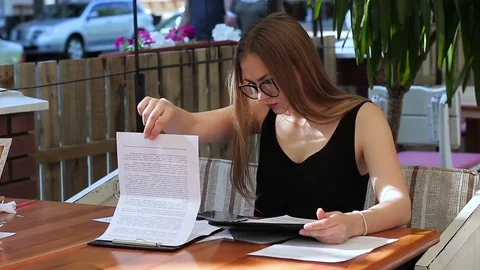 A woman is working in a cafe. With a tablet, documents and a smartphone Video stock 75333666