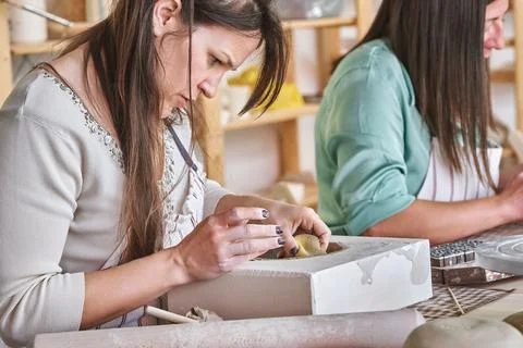 Woman working with clay while making a pottery craft in a workshop. Fotos Stock