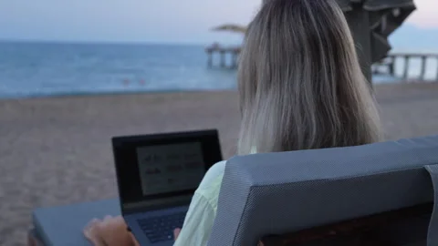 A woman is working on a computer at the beach. Stock-Footage 282237234