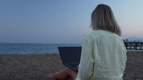 A woman is working on a computer at the beach. Stock Footage 282237308
