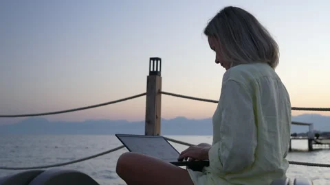 A woman is working on a computer at the beach. Stock Footage 282237496