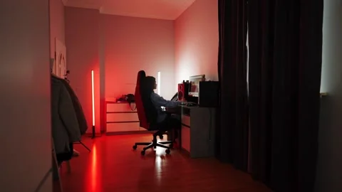 Woman working on computer in a dimly lit room with colored lights Stock Footage 314093959