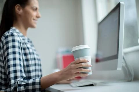 Woman Working At Computer Drinking From Reusable Takeaway Cup Stock Photos