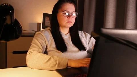 Woman working on computer late evening at home office. Concentrated female Stock Footage 304039481