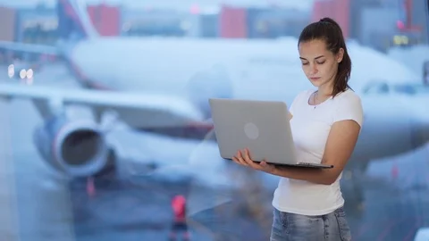 Woman working on computer near window at airport, blurred airplane on background Stock Footage 122230705