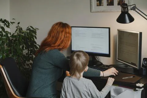 Woman working on computer while child looking and waiting Stock Photos