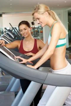 Woman Working With Female Personal Trainer On Running Machine In Gym Stock Photos