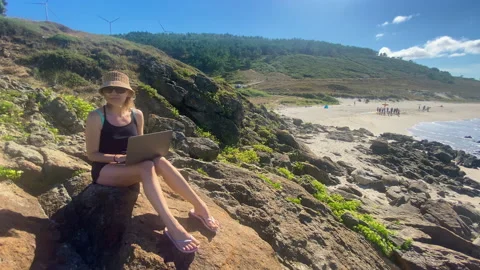 Woman working with her computer on the beach, like a digital nomad Stock Footage 240036244