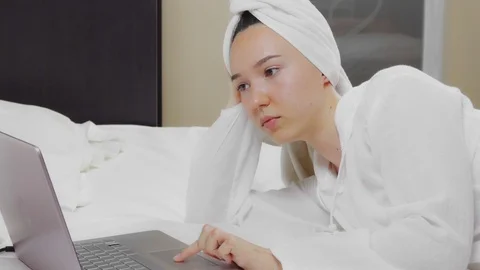 Woman working with her laptop while sitting on a snow-white bed, top view Vídeo Stock 125366367