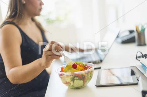 Woman working in home office and eating salad Stock Photos