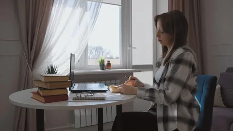 Woman working from home taking notes and typing on laptop Stock Footage 314609076