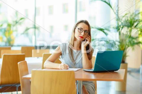 Woman working with a laptop and talking on the cell phone Stock Photos