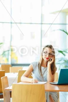 Woman working with a laptop and talking on the cell phone Stock Photos