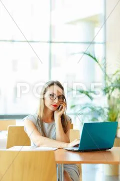 Woman working with a laptop and talking on the cell phone Stock Photos