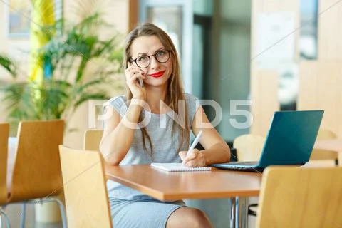 Woman working with a laptop and talking on the cell phone Stock Photos