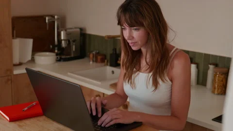 Woman Working on Laptop While Checking Phone in Home Kitchen Stock Footage 332257847