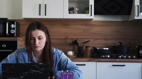 Woman working at laptop while sitting at the table in the kitchen, at home Stock Footage 152876228