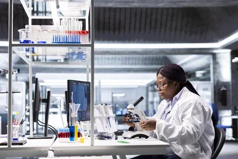 Woman working with microscope and sample tray in chemistry lab 스톡 사진