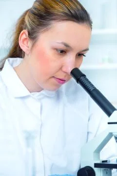 Woman working with a microscope in a lab Stock Photos