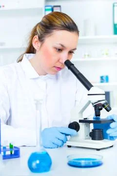 Woman working with a microscope in a lab Stock Photos