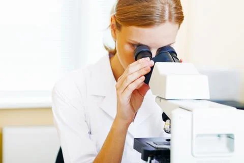 Woman working with a microscope. Stock Photos