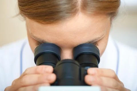 Woman working with a microscope. Stock Photos
