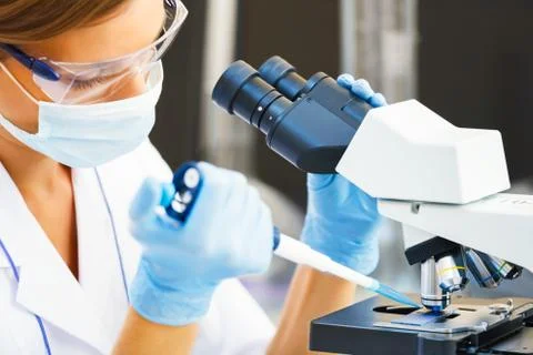 Woman working with a microscope. Stock Photos