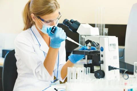 Woman working with a microscope. Stock Photos