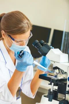 Woman working with a microscope. Stock Photos