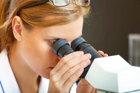 Woman working with a microscope. Stock Photos