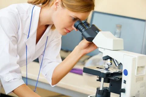 Woman working with a microscope. Stock Photos