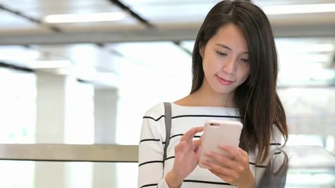 Woman working on mobile phone in train station hall Stock Footage