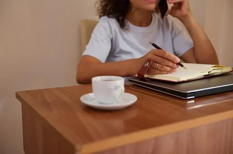 Woman Working on Notebook While Taking a Phone Call with a Cup of Coffee Near Stock Photos