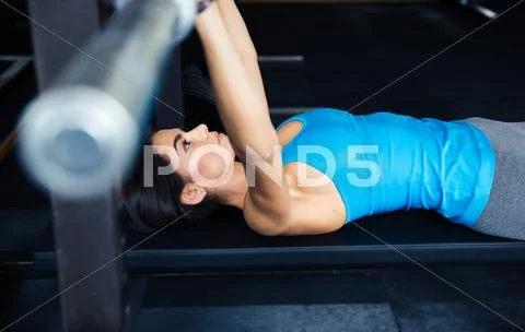 Woman working out with barbell on bench Stock Photos