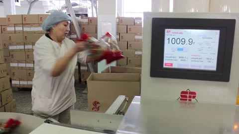 The woman working the packer puts candy bars in the box. Stock Footage 128643296