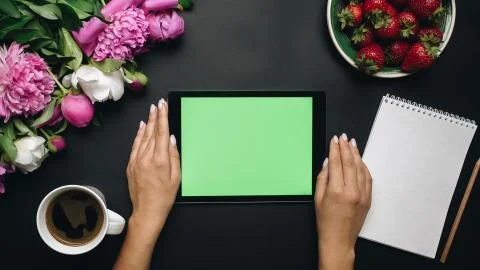Woman working on tablet computer device with green screen. Beautiful white and Stock Photos