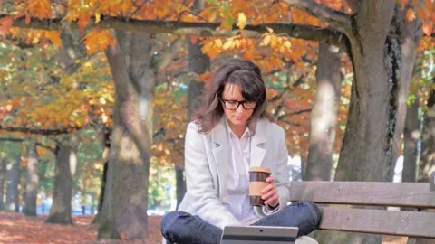 Woman working with tablet sitting on the bench, autumn in park 스톡 동영상 131224976