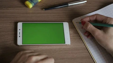 Woman in workplace using his smartphone with green screen. Female hands using Stock Footage 101970885