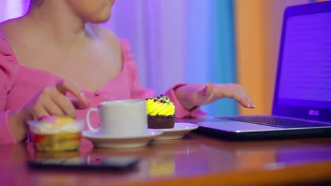 Woman works on a computer eats pastries and drinks coffee. Stock Footage 119335122
