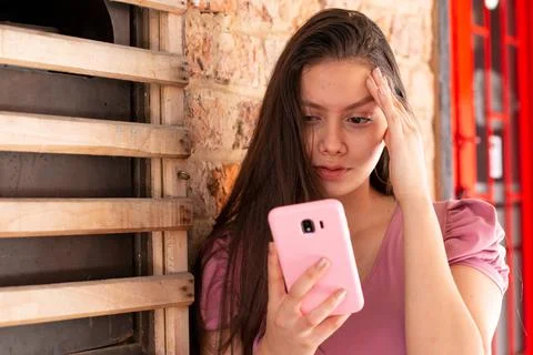 Woman with worried expression while looking at her cell phone. Stock Photos